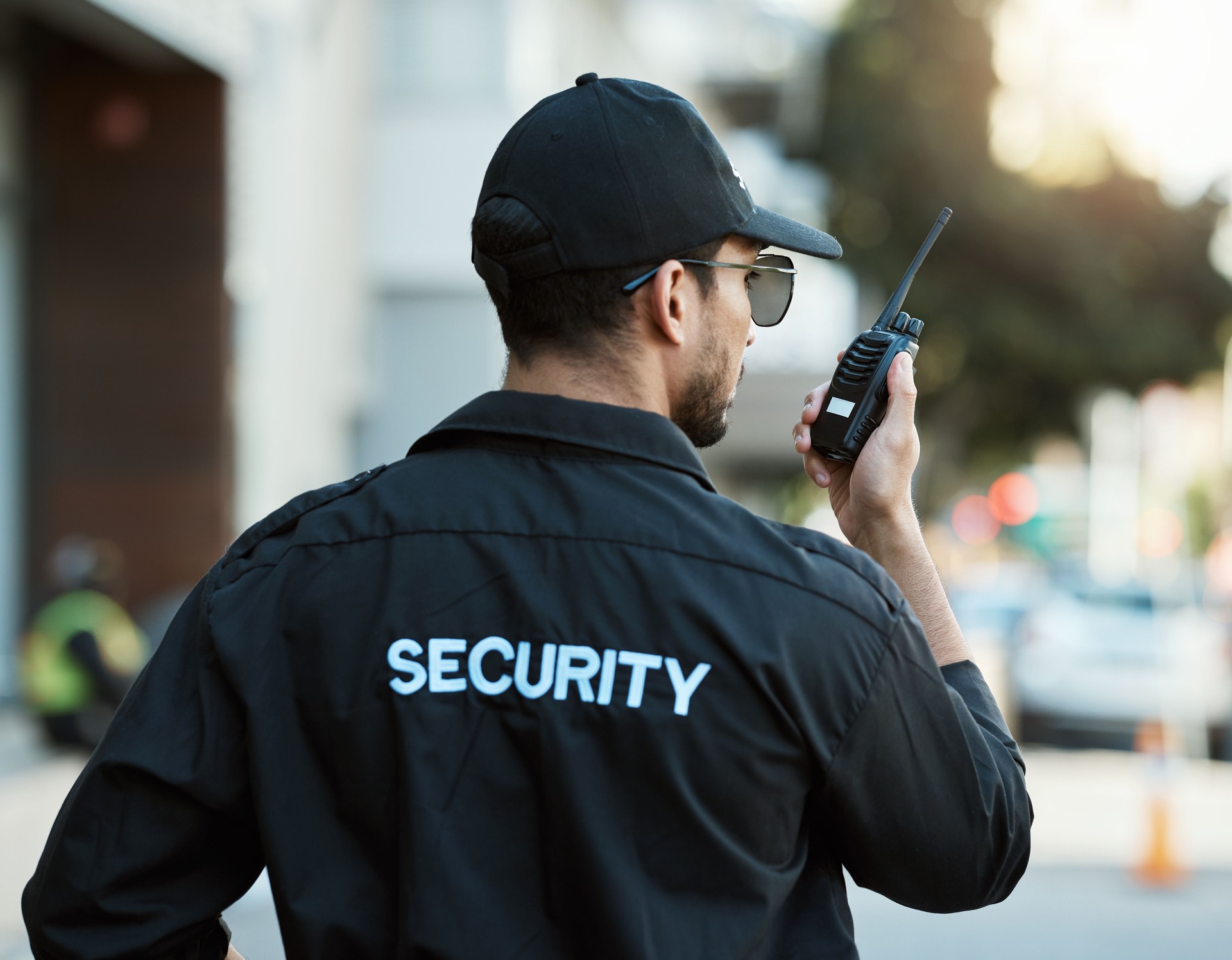 Radio, homme et un agent de sécurité ou un agent de sécurité à l’extérieur sur une route de la ville pour la communication. Dos d’une personne avec un talkie-walkie dans la rue urbaine pour signaler un crime aux fins d’enquête et de surveillan